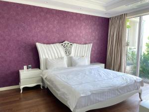 a bedroom with a white bed with a purple wall at Ocean Star Resorts - Seopjikoji in Seogwipo