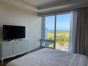 ein Schlafzimmer mit einem Bett und einem großen Fenster in der Unterkunft Ocean Star Resorts - Seopjikoji in Seogwipo