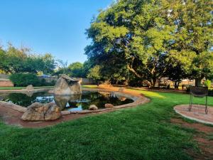 a pond in a park with a statue in the grass at Eastwoods Lodge in Springs