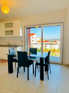 une salle à manger avec une table, des chaises et une grande fenêtre dans l'établissement Apartamento ALTAMIRA T2 SERRA SHOPPING, à Covilhã