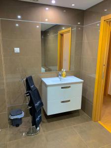 uma casa de banho com um lavatório branco e um espelho. em Apartamento ALTAMIRA T2 SERRA SHOPPING na Covilhã