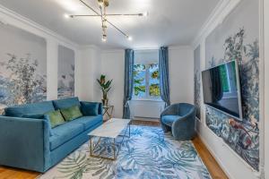a living room with a blue couch and a tv at Garden of Eden 1-bedroom apartment – Lakefront in Territet