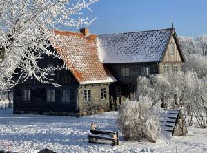 una vecchia casa nella neve con una panchina davanti di Tilia authentic home, butikowe apartamenty nad morzem a Mikoszewo