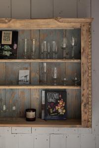 una estantería de madera con copas de vino y un libro en Tilia authentic home, butikowe apartamenty nad morzem en Mikoszewo