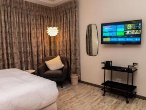 a bedroom with a bed and a chair and a flat screen tv at Sou House in Louis Trichardt