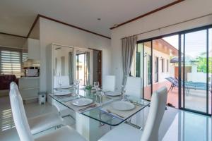 een eetkamer met een glazen tafel en witte stoelen bij Private 4 Bedroom Pool Villa NB6 in Hua Hin