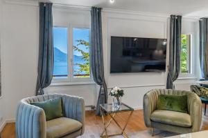 a living room with two chairs and a tv at Soft Glam 1-bedroom appt - Lake & Mountain View in Montreux