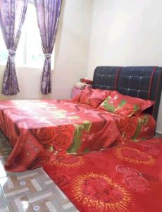 a bedroom with two beds with red blankets and roses at Nor Su Homestay in Kampong Alor Gajah