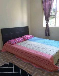 uma cama com um cobertor rosa e uma janela em Nor Su Homestay em Kampong Alor Gajah