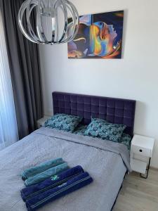 a bedroom with a bed with a purple headboard and a chandelier at Mikis apartament, Mano Jūra 2, Kunigiškiai in Palanga