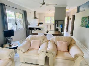 a living room with two white couches with pink pillows at The Palms 3 bedroom comfort in quiet court in Darwin