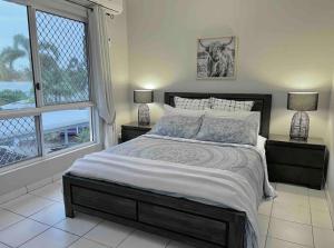 ein Schlafzimmer mit einem großen Bett und zwei Fenstern in der Unterkunft The Palms 3 bedroom comfort in quiet court in Darwin