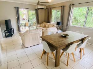 - un salon avec une table en bois et des chaises blanches dans l'établissement The Palms 3 bedroom comfort in quiet court, à Darwin