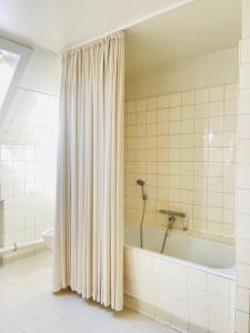 a bathroom with a tub and a shower curtain at aday - Frederikshavn City Center - Charming double room in Frederikshavn