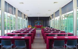 a conference room with red tables and chairs and a stage at K Gallery Hotel in Pasuruan