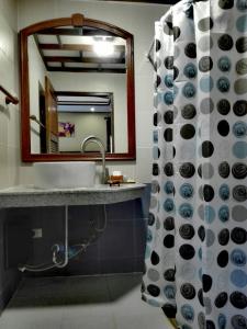 ein Badezimmer mit einem Waschbecken, einem Spiegel und einem Duschvorhang in der Unterkunft Luang Chumni Village in Phra Nakhon Si Ayutthaya