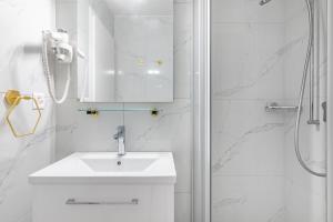 uma casa de banho branca com um lavatório e um chuveiro em Secret Garden studio – Lakefront em Montreux