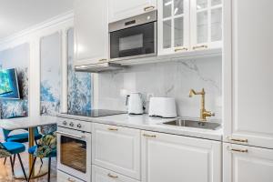uma cozinha branca com armários brancos e um lavatório em Secret Garden studio – Lakefront em Montreux