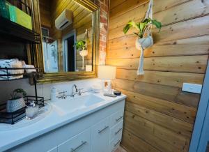 ein Badezimmer mit einem Waschbecken und einer Holzwand in der Unterkunft Treehouse Hideouts - Ground Level - Heygarth House Townhouse - Port of Echuca in Echuca