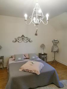 a bedroom with a large bed and a chandelier at La maison Maria Rosa in Onzain