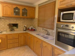 cocina con armarios de madera, fregadero y microondas en Luxurious house at Coromandel en La Rotraite
