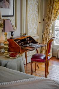 - une chambre avec un bureau, une chaise et une lampe dans l'établissement Château Pape Clément, à Pessac