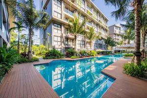 a swimming pool in front of a building with palm trees at Diamond CONDO by VС in Bang Tao Beach