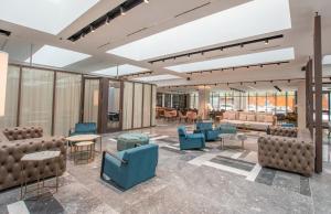 a lobby with blue chairs and tables and windows at Hotel Giralda Center in Seville