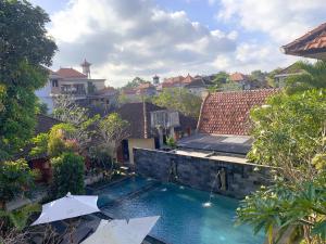 an outdoor swimming pool with umbrellas in a yard at Merthayasa Bungalow 2 in Ubud