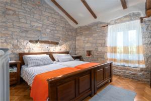 a bedroom with a bed and a stone wall at Villa Janko in Sveti Lovreč Pazenatički