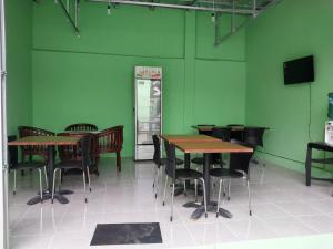 a dining room with green walls and tables and chairs at Omah 365 Homestay in Yogyakarta