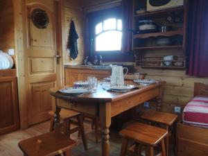 een keuken met een houten tafel met stoelen en een raam bij Les Roulottes de la Ferme des Chanaux in Saint-Julien-dʼAnce