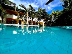 a swimming pool in front of a building with palm trees at Alona Swiss Resort in Panglao Island