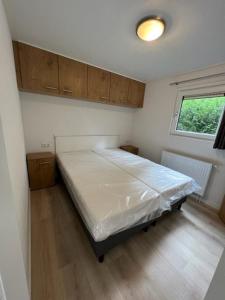 a bedroom with a bed in a room with a window at Chalet Hoenderloo in Hoenderloo