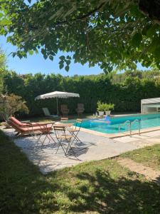 einen Pool mit einem Tisch, Stühlen und einem Sonnenschirm in der Unterkunft Cabanon Ecurie Maestoso in Lançon-Provence