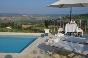 a swimming pool with an umbrella and a table and chairs at Casa Magnolia in Terricciola