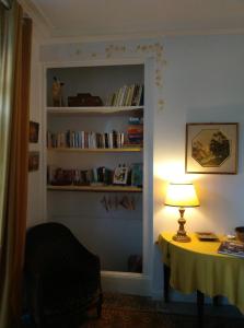 ein Zimmer mit einem Tisch mit einer Lampe und einem Bücherregal in der Unterkunft Le Voltaire in Souppes-sur-Loing