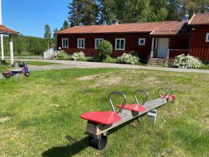 un banco rojo sentado en el césped en un patio en Skogshemmet, en Ludvika