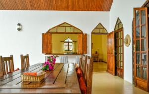 a dining room with a wooden table with flowers on it at Garden Beach Villa Zanzibar in Kilima Juu Pwani