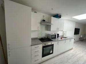a kitchen with white cabinets and a microwave at Luxury 2 bedroom apartment near the O2 and Canary Wharf in Eltham
