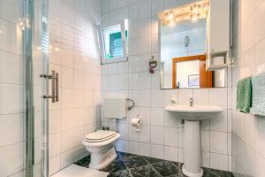 a white bathroom with a toilet and a sink at Apartmani Vukičević in Vodice