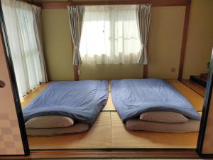 a bedroom with two beds in front of a window at SIBARIAN Guest House in Kaga