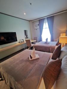 um quarto de hotel com duas camas e uma televisão de ecrã plano em Yes Hotel Pandi Bulacan em Pandi