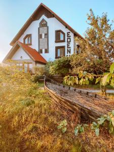 uma casa branca com uma cerca de madeira em frente em Pensiunea EDEN em Crisan