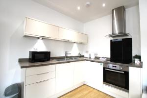 a kitchen with white cabinets and a black appliance at Corbiere House @ Short Stays in Basingstoke
