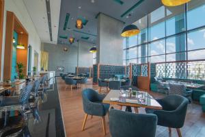 a restaurant with tables and chairs and windows at Dana Rayhaan by Rotana in Dammam