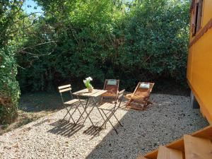 une table avec deux chaises et une table avec un vase dans l'établissement La Roulotte du Herdal, à Profondeville