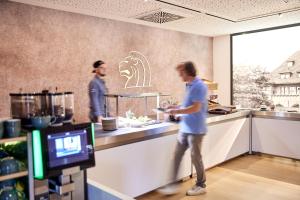 two men standing in a kitchen preparing food at Kasino Hotel in Leverkusen