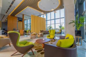 a lobby with chairs and tables and windows at Dana Rayhaan by Rotana in Dammam