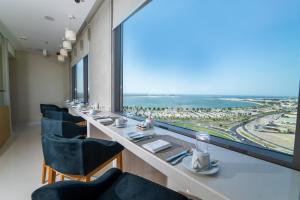 een restaurant met een lange tafel met stoelen en een groot raam bij Dana Rayhaan by Rotana in Dammam